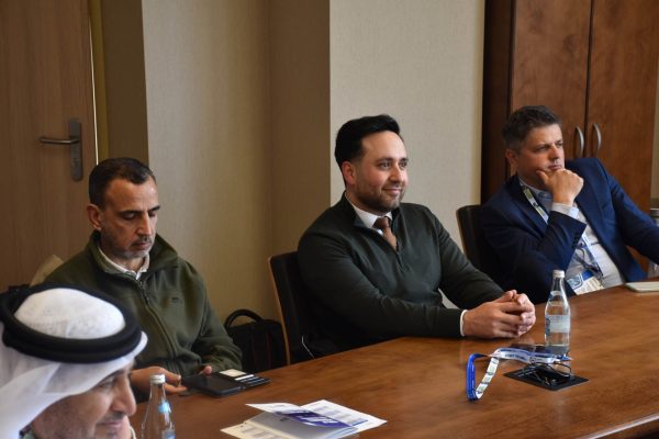 Uczestnicy zasiadają przy drewnianym stole podczas spotkania konferencyjnego.