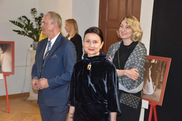 Troje gości pozuje w sali uroczystej kolacji.