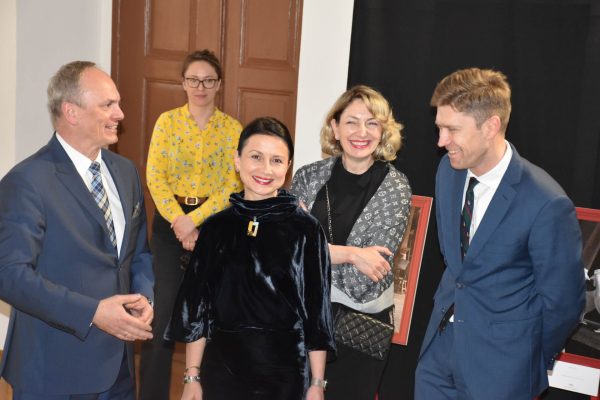 Uśmiechnięci goście gali rozmawiają przy wejściu.