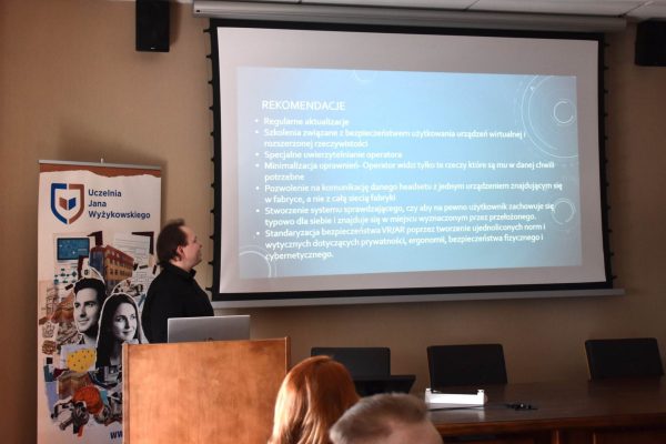 Prelegent wskazuje slajd z wnioskami podczas konferencji studenckiej.