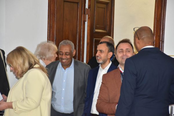 Grupa gości rozmawia przy drewnianych drzwiach podczas gali.