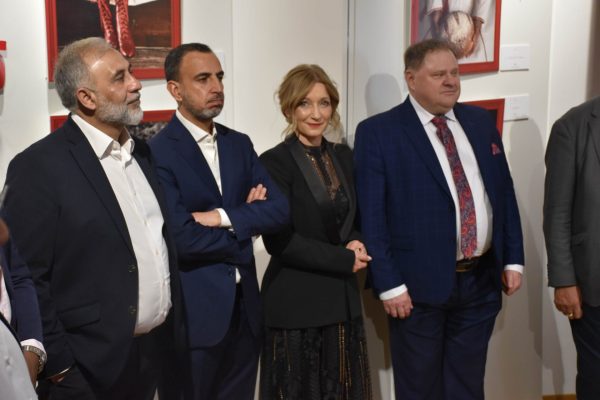 Czworo gości w eleganckich strojach słucha prowadzących galę.