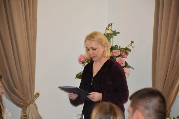 Prowadząca uroczystą kolację odczytuje tekst z teczki.