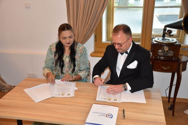 Sygnatariusze przeglądają i podpisują dokumenty współpracy między uczelniami.