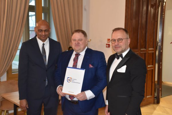 Wyróżniony uczestnik prezentuje dokument między dwoma przedstawicielami konferencji.