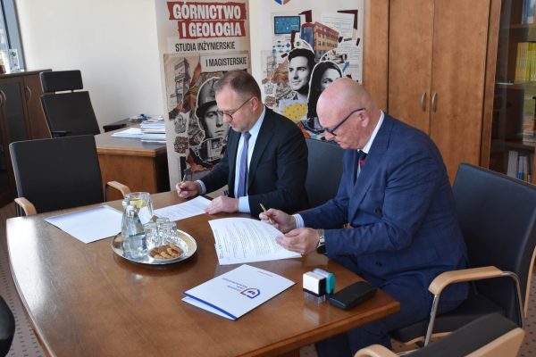 Sygnatariusze przeglądają dokumenty porozumienia przy biurku.