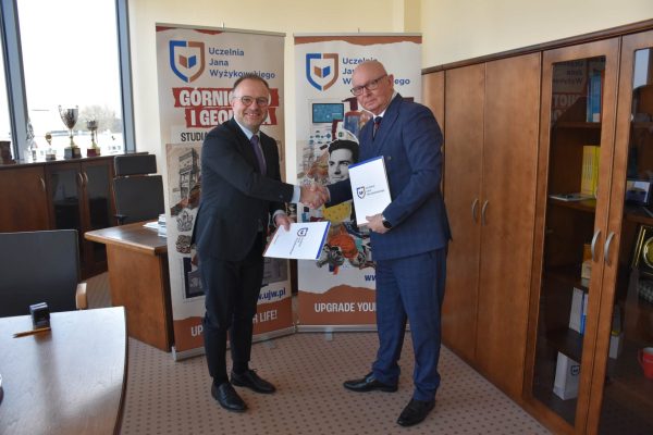 Sygnatariusze pozują z porozumieniem na tle plansz UJW.