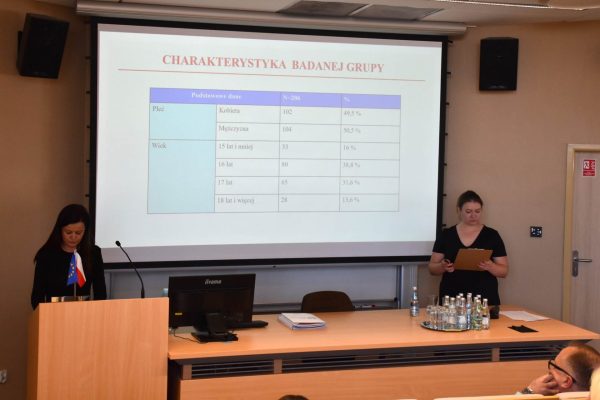 Dwie prelegentki omawiają tabelę z charakterystyką badanej grupy.