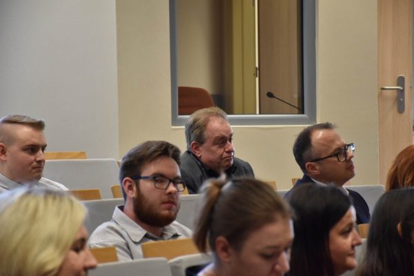 Uczestnicy konferencji słuchają wystąpienia w sali wykładowej.