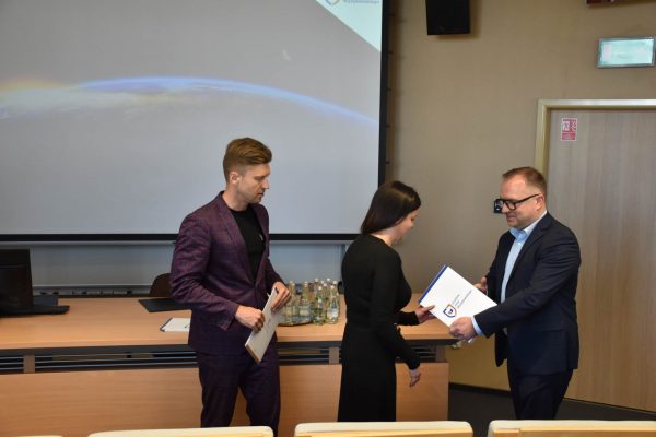 Organizator przekazuje dokument uczestniczce w czarnym stroju.