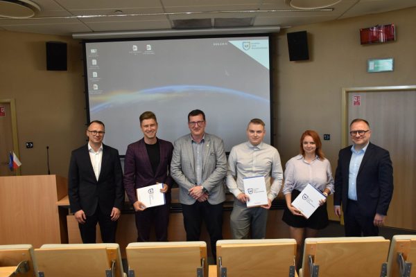 Grupa uczestników i organizatorów prezentuje dokumenty konferencyjne.