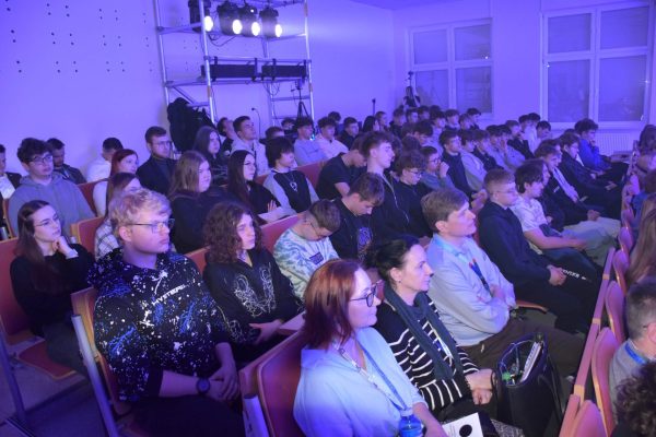 Uczestnicy konferencji obserwują prezentację w wypełnionej auli.