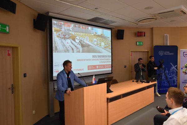 Mężczyzna w niebieskiej marynarce przemawia przy mównicy podczas Digital Transformation Forum.