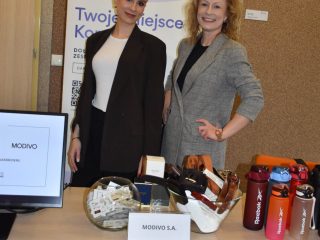 Dwie kobiety przy stoisku MODIVO z obuwiem i gadżetami podczas Dnia Drzwi Otwartych UJW.