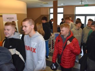 Grupa odwiedzających przechodzi między stoiskami na korytarzu UJW.