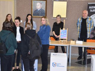 Rozmowy przy stoisku informacyjnym UJW pod portretem patrona uczelni.