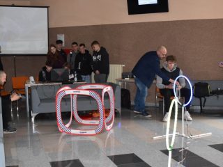 Pokaz małych dronów w sali z bramkami toru przeszkód.