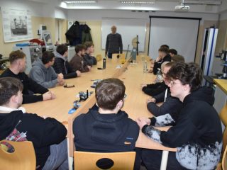 Uczestnicy Dnia Drzwi Otwartych przy długim stole w pracowni technicznej UJW.