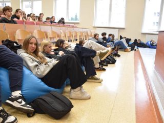 Uczestnicy spotkania na niebieskich pufach w przedniej części auli UJW.