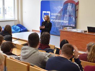 Prelegent z mikrofonem przed publicznością w auli UJW.