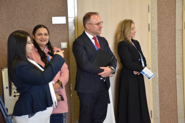 Uczestniczka konferencji robi zdjęcie telefonem, obok stoją inni goście.