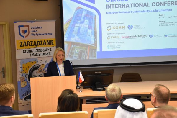 Prowadząca otwiera spotkanie przy mównicy na tle planszy konferencji CIRCLE.