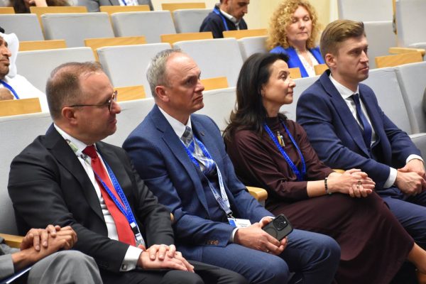 Goście konferencji słuchają wystąpienia w pierwszym rzędzie sali.