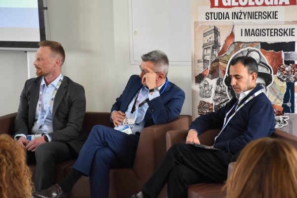 Trzej paneliści siedzą obok siebie podczas dyskusji konferencyjnej.