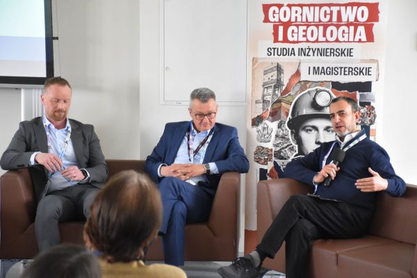 Panelista w granatowej marynarce mówi do mikrofonu i gestykuluje.