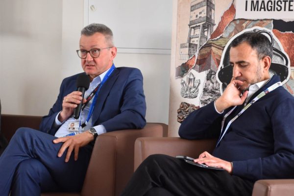Wypowiedź panelisty w niebieskim garniturze na tle planszy UJW.