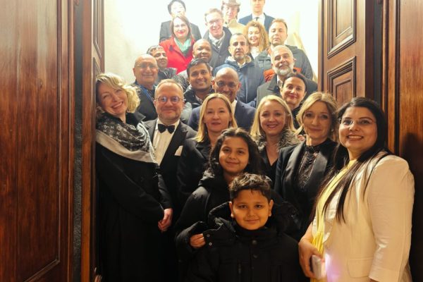 Duża grupa gości pozuje na schodach w otwartych drzwiach.