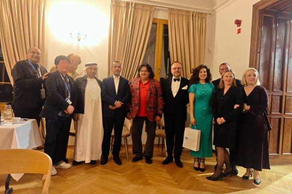 Grupa uczestników i artystów pozuje w sali z fortepianem.