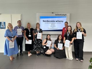 Uczestnicy spotkania w Bosch Rexroth pozują z certyfikatami na tle ekranu powitalnego.