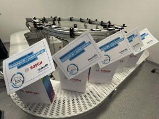 Certyfikaty Bosch Rexroth ustawione na stole przy stanowisku demonstracyjnym.