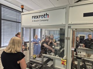Uczestniczki oglądają mechanizmy wewnątrz osłoniętego stanowiska Rexroth.