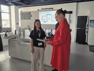 Kobieta w czerwonej sukience rozmawia z uczestniczką przy urządzeniach w centrum Bosch Rexroth.