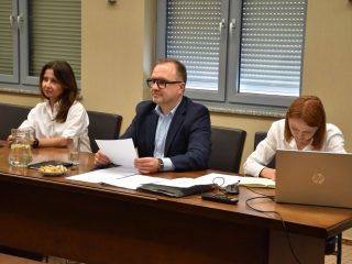 Troje uczestników posiedzenia Senatu UJW pracuje z dokumentami i laptopem.