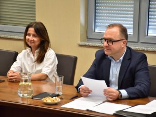 Kobieta w białej bluzce i mężczyzna z dokumentem podczas posiedzenia Senatu UJW.