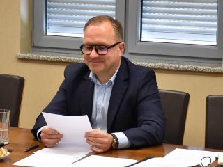 Uczestnik posiedzenia Senatu UJW w granatowej marynarce trzyma dokument.