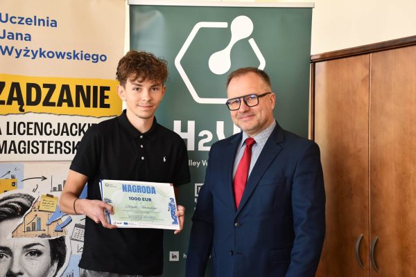 Laureat konkursu prezentuje nagrodę obok przedstawiciela UJW.