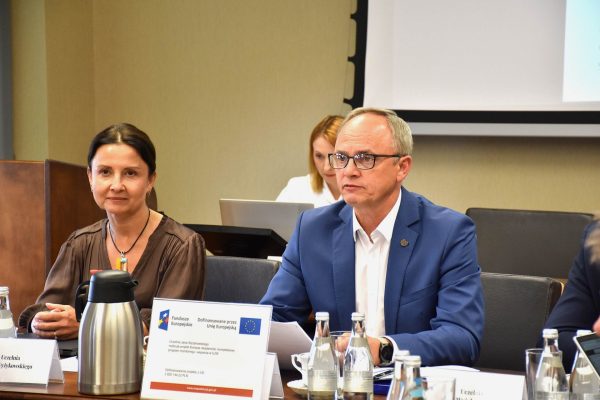 Dwoje uczestników Konwentu słucha obrad przy stole.