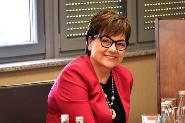 Uśmiechnięta uczestniczka w czerwonej marynarce podczas obrad.