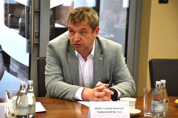 Przedstawiciel INOVA przemawia przy stole ze splecionymi dłońmi.