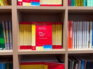 Regał z podręcznikami matematycznymi w czerwono-żółtych okładkach.