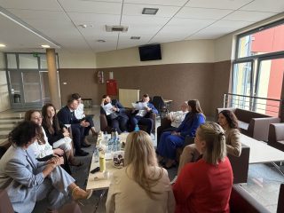Uczestnicy obron zarządzania rozmawiają przy poczęstunku na korytarzu uczelni.