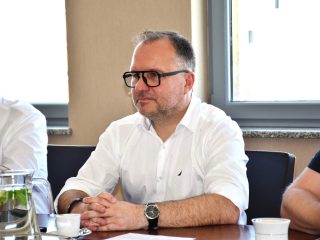 Mężczyzna w białej koszuli i okularach przy stole podczas spotkania z KGHM INOVA.