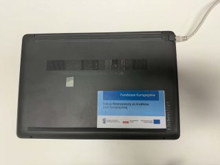 Spód laptopa z etykietą zakupu finansowanego ze środków Unii Europejskiej.